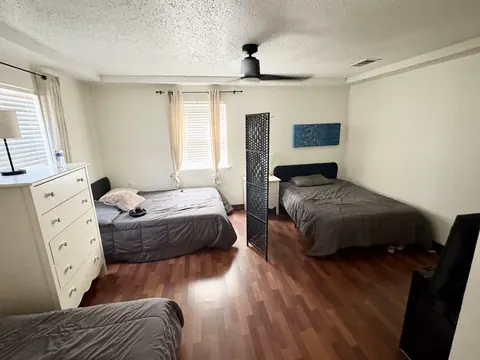 Shared bedroom with three beds and hardwood floors